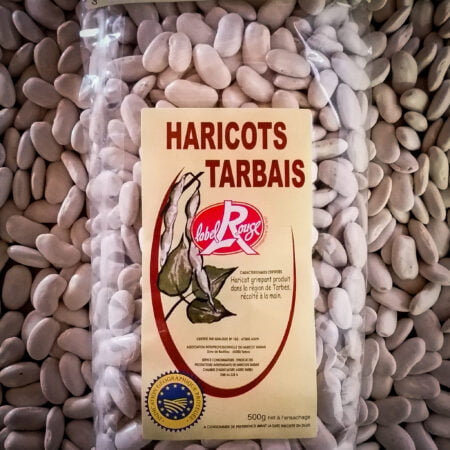 Photo d'un paquet de Haricots Tarbais Label Rouge IGP posé sur un lit de Haricots Tarbais