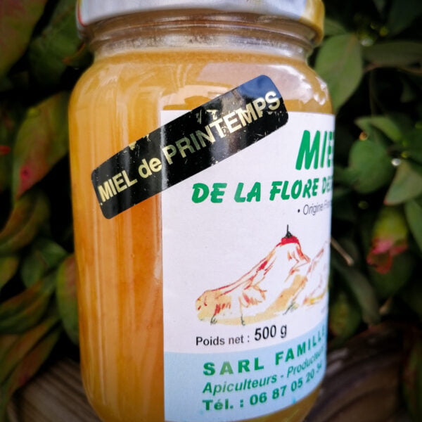 Vue de côté d'un pot de miel de printemps de la flore des Pyrénées produit par la famille Legrand à Bégole dans les Hautes-Pyrénées