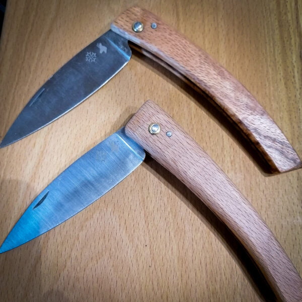 Deux Couteaux de poche avec manche en bois et lame en acier inoxydable sur laquelle est gravé la croix occitane, ils sont fabriqués dans les hautes-pyrénées