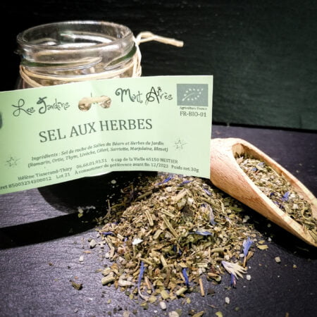 Petit pot de sel aux herbes de 30g des jardins Mont Arès posé sur une ardoise avec une petite cuillère à sel et épices.