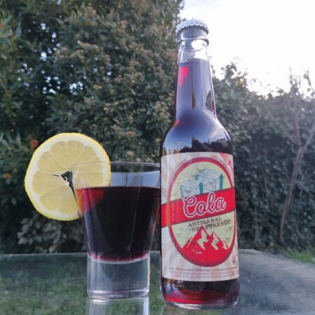 bouteille en verre de 33cl de cola artisanal avec un verre rempli et une tranche de citron