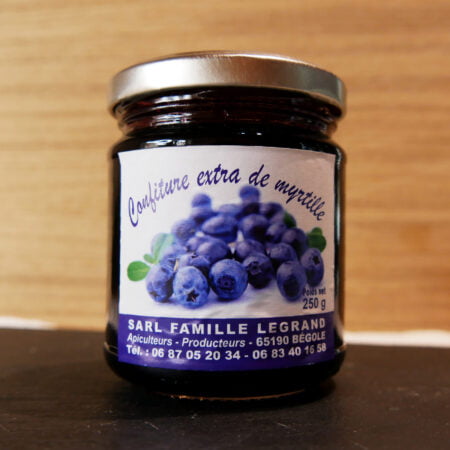 Pot de 250g de confiture à la myrtille produit des hautes pyrénées par la famille legrand posée devant une plaque de bois