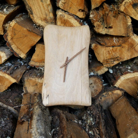 Horloge murale en bois présentée devant un tas de bois