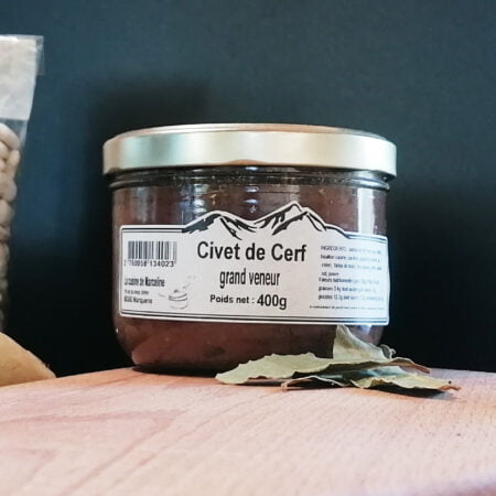 Petite conserve de Civet de Cerf grand veneur de 400g de la cuisine de Marceline posée sur une planche à découper avec 3 feuilles de laurier, des pommes de terre et un paquet de haricots Tarbais