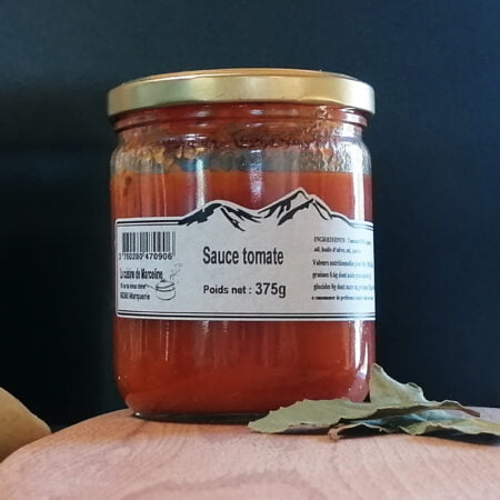 Pot de sauce tomate posé sur une planche en bois avec quelques feuilles de laurier