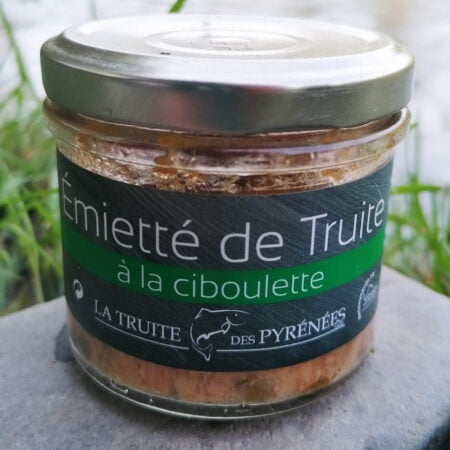 Conserve d'émiettés de truite à la ciboulette posé sur une pierre devant une rivière