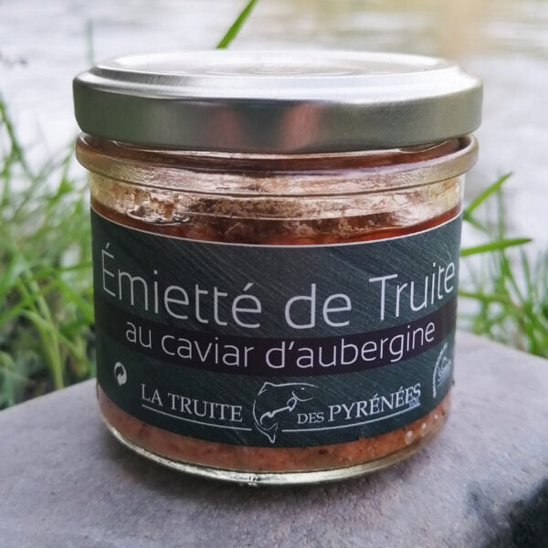 Photo d'un pot d'émietté de truite au caviar d'aubergine de la maison La truite des Pyrénées posé au bords de la rivière.