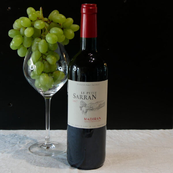 Bouteille de vin rouge le petit Sarran 2017 madiran accompagnée d'un verre et d'une grappe