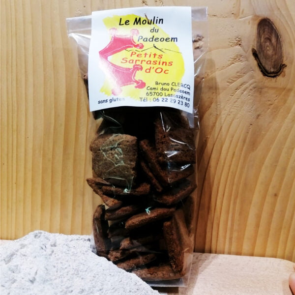 Photo d'un sachet de petits Sarrasins d'Oc posé sur une planche en bois avec un petit tas de farine de Sarrasins, produit par Le Moulin du Padeoem.
