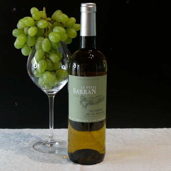 Bouteille de vin blanc Le petit Sarran millésime 2018 pacherenc du vic-bilh sec avec du raisin dans un verre de vin à coté