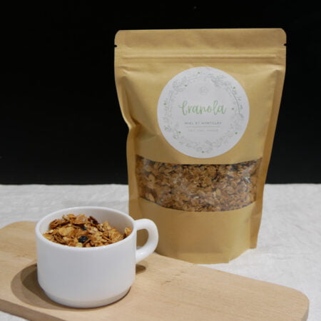 Sachet de granola marron avec tasse pleine sur planche en bois