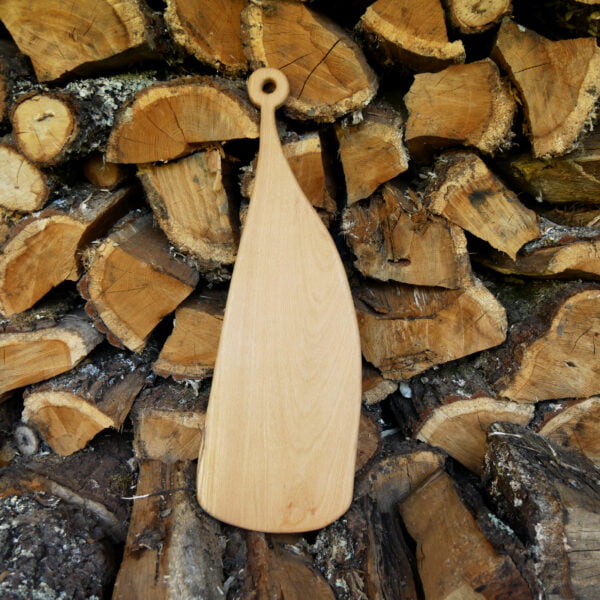 Grande planche en bois à découper posée à la verticale sur des fagots de bois