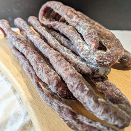 Saucisses sèches de la ferme Lalaque, produit des Hautes-Pyrénées posées sur une planche en bois