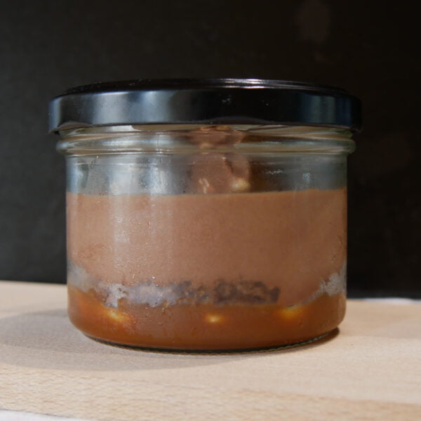 Dessert type verrine saveur cacao et cacahuètes dans un pot en verre sur un planche en bois
