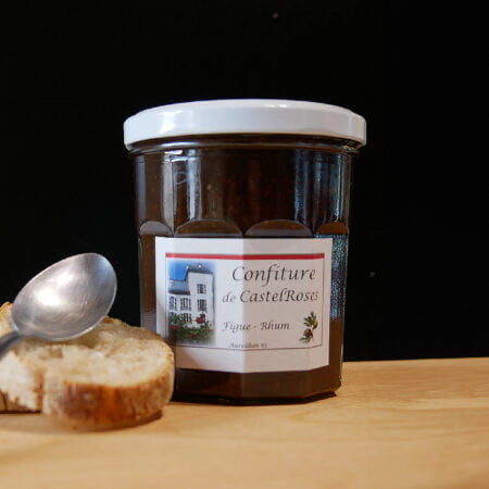 Confiture de chez Castelrose à la figue et au Rhum posé sur une planche en bois et avec de quoi tartiner à coté