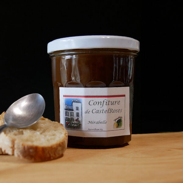 Pot de confiture à la mirabelle accompgné d'une cuillère et d'un morceau de pain, le tout posé sur une planche