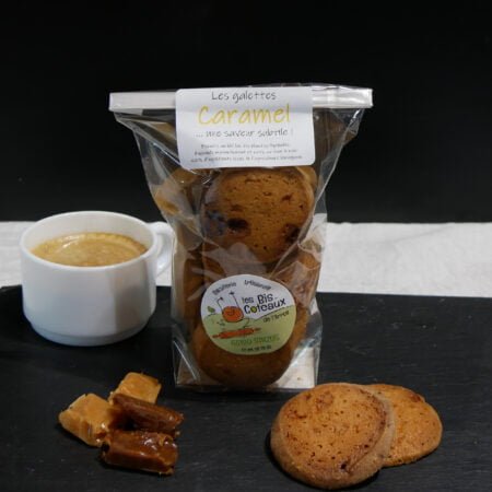 Biscuit au caramel de chez Bis-Côteaux emballé dans un petit sachet et entouré de petit caramel et d'un café pour une mise en scène de petit déjeuner, deux gateau sont sortis de l'emballage et sont posés devant