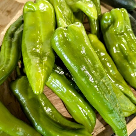 une douzaine de poivrons verts long sur un meuble en bois