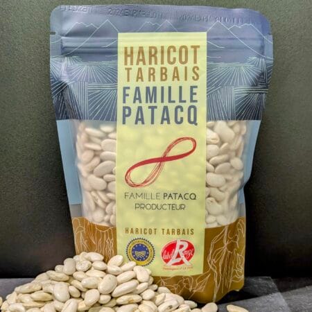 Un paquet de 250g de haricots tarbais. Un arrière plan entièrement noir. Devant, une pile de Haricots Tarbais séchés