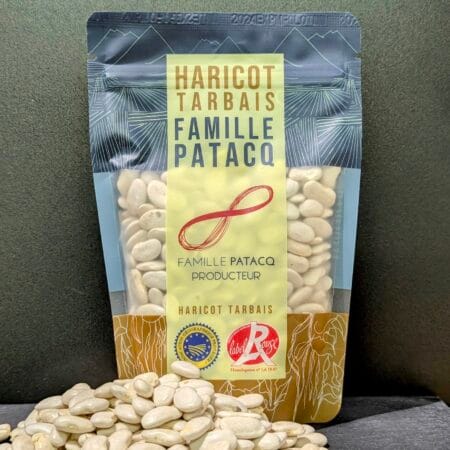 Fond Noir sur lequel prone un paquet de Haricots Tarbais de la Famille Patacq à Jer, devant lequel est disposé un petit tas de haricots Tarbais