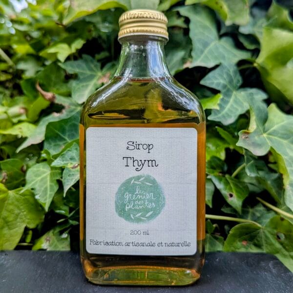 Une flasque de Sirops au Thym mise en valeur par un fond végétal et un socle en adroise