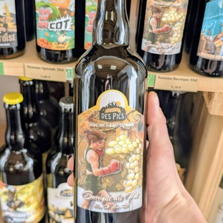 Le photographe tiens une biere barrique des pics 2025 au cognac dans sa main devannt le rayon bière
