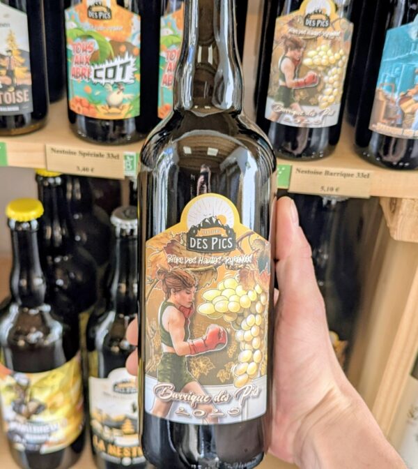 Le photographe tiens une biere barrique des pics 2025 au cognac dans sa main devannt le rayon bière