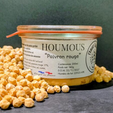 Un fond noir, devant lequel est posé un pot de houmous au poivron rouge de chez "L'Amour Conserve", recouvert de pois chiches